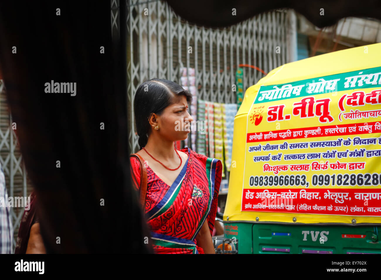 Eine Frau, die eine überfüllte Straße in Varanasi, Uttar Pradesh, Indien, überquert. Stockfoto