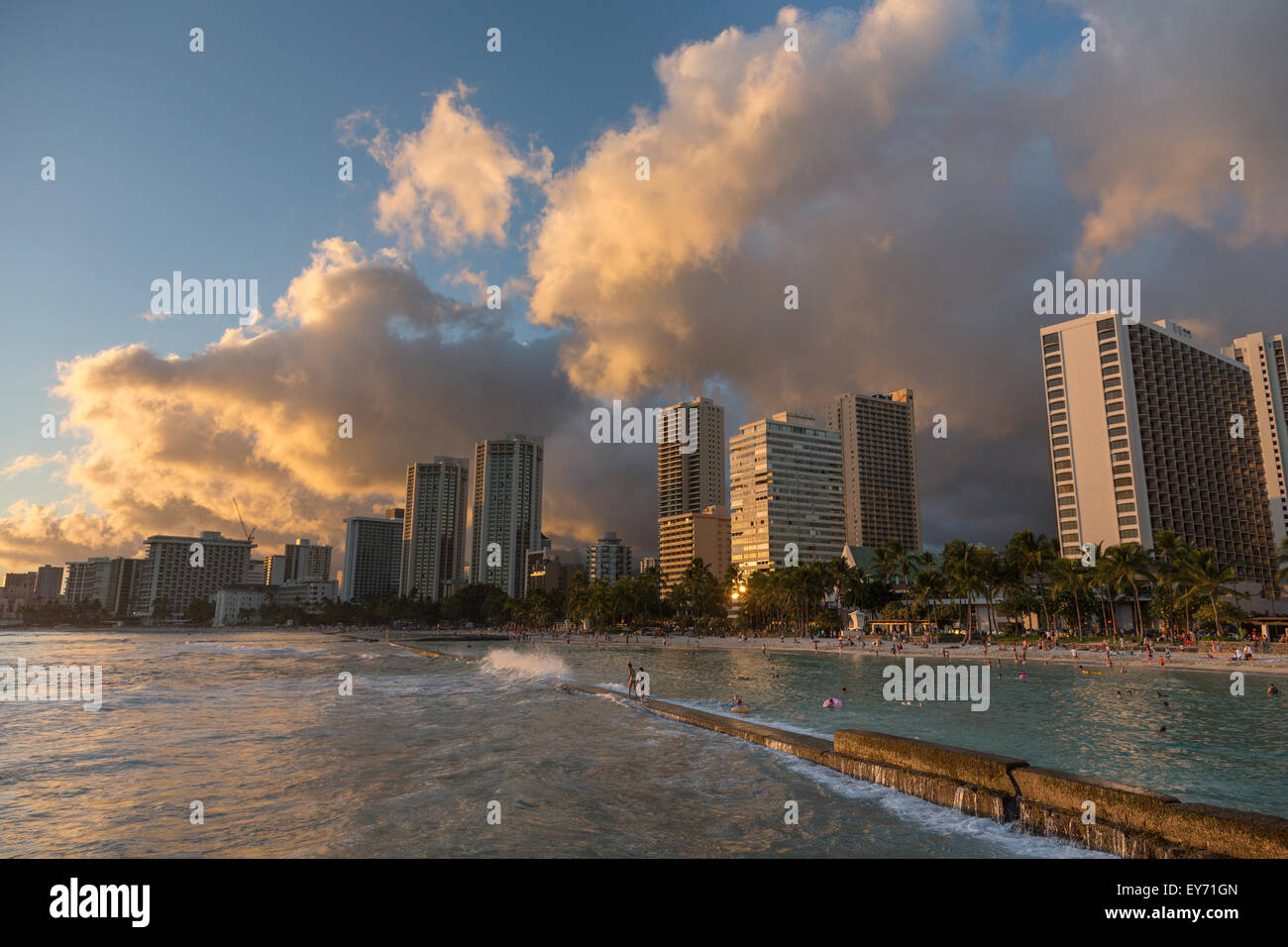 Prince Kuhio Beach in Waikiki mit Menschen zu Fuß entlang der Mole bei Sonnenuntergang. Stockfoto
