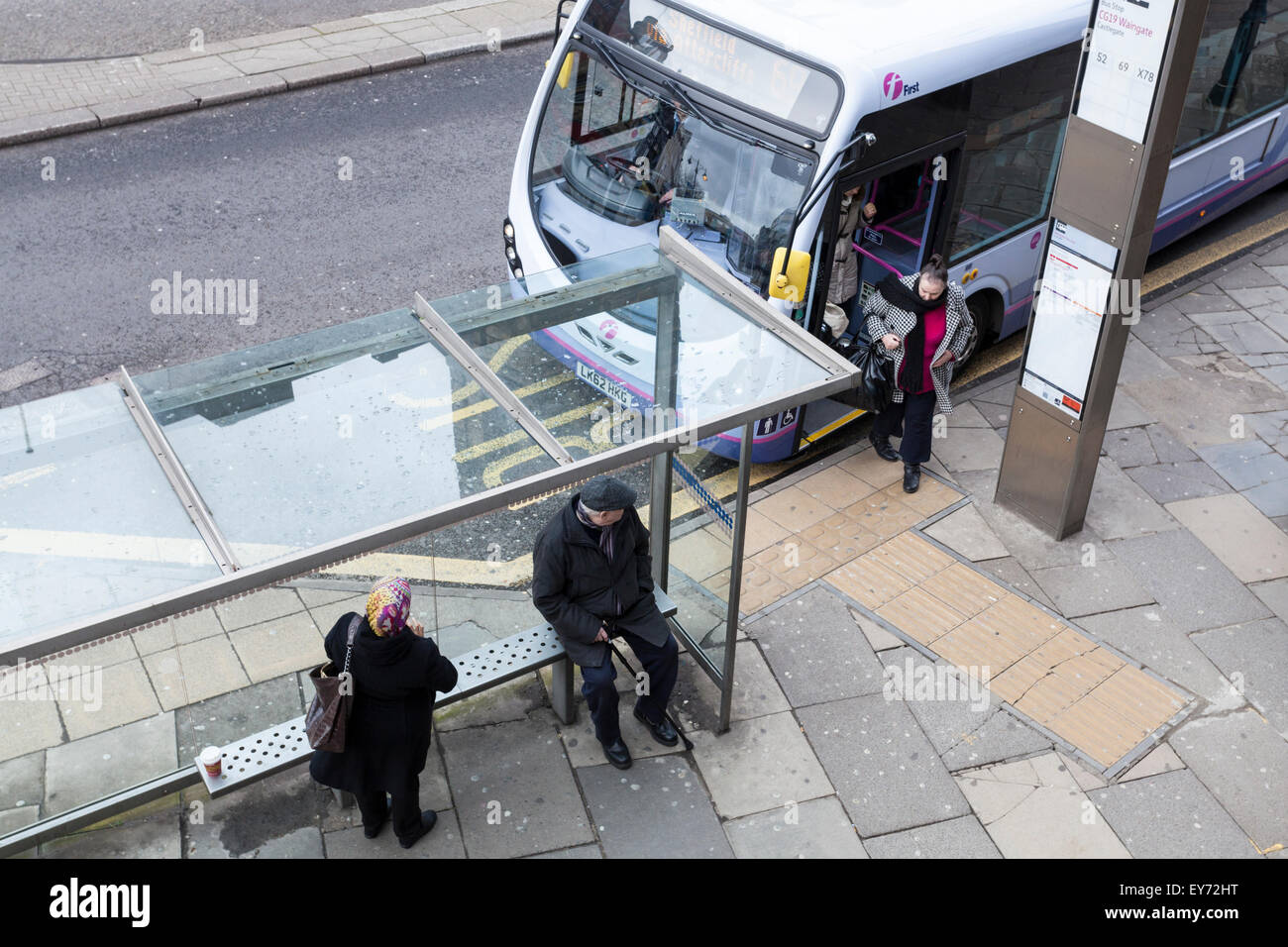 UK öffentliche Verkehrsmittel. Die Menschen warten an der Bushaltestelle, während eine andere Person wird immer aus einem Bus in Sheffield, England, Großbritannien Stockfoto