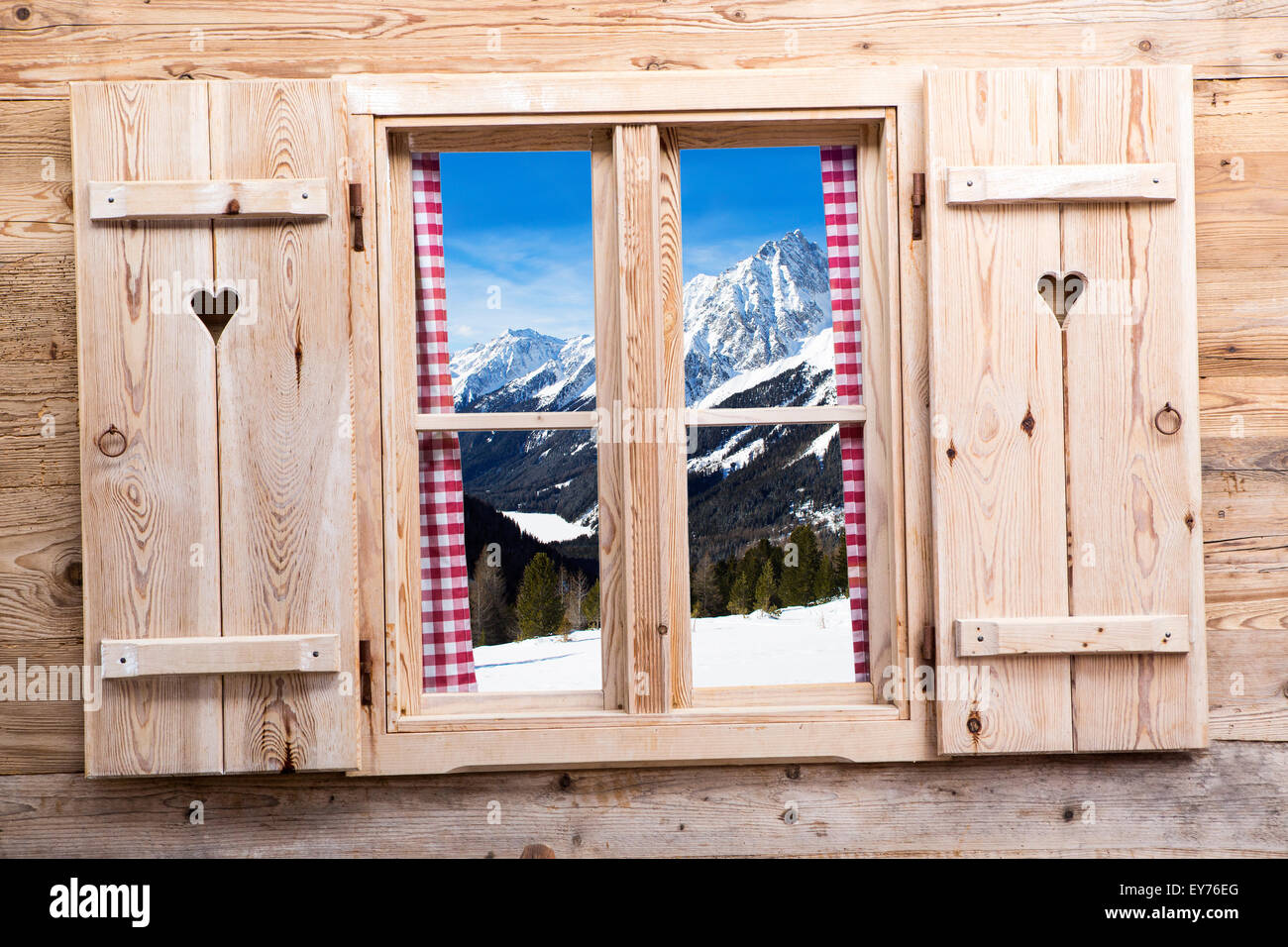 Holzfenster mit schneebedeckten Bergen als Reflexionen Stockfoto