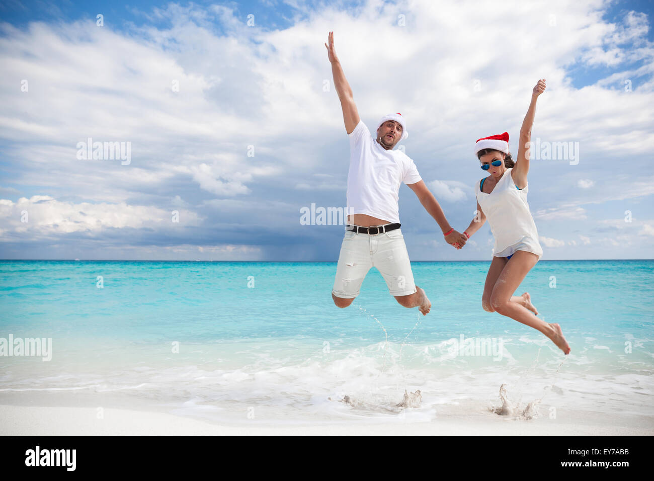 Glückliches Paar feiert Weihnachten am Strand, in die Luft springen Stockfoto