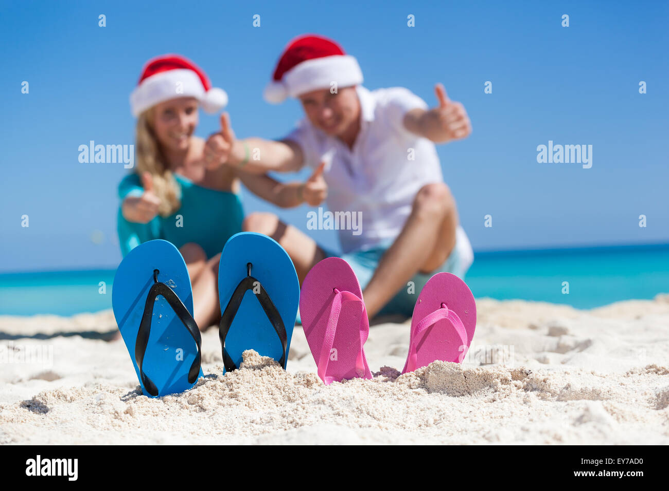 Karibik Weihnachten Urlaub am sandigen Strand. Zwei paar Flip flops stehen in einem Sand auf Hintergrund mit emotionalen Paar. Stockfoto