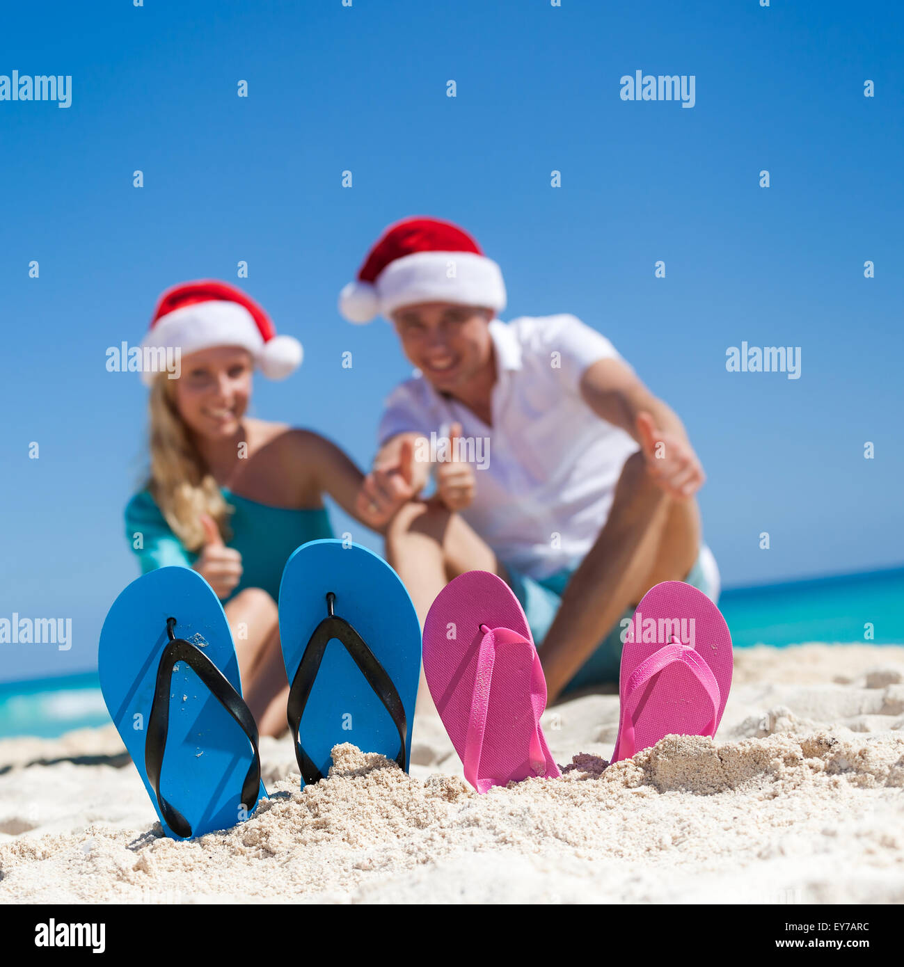 Karibik Weihnachten Urlaub am sandigen Strand. Zwei paar Flip flops stehen in einem Sand auf Hintergrund mit emotionalen paar Stockfoto