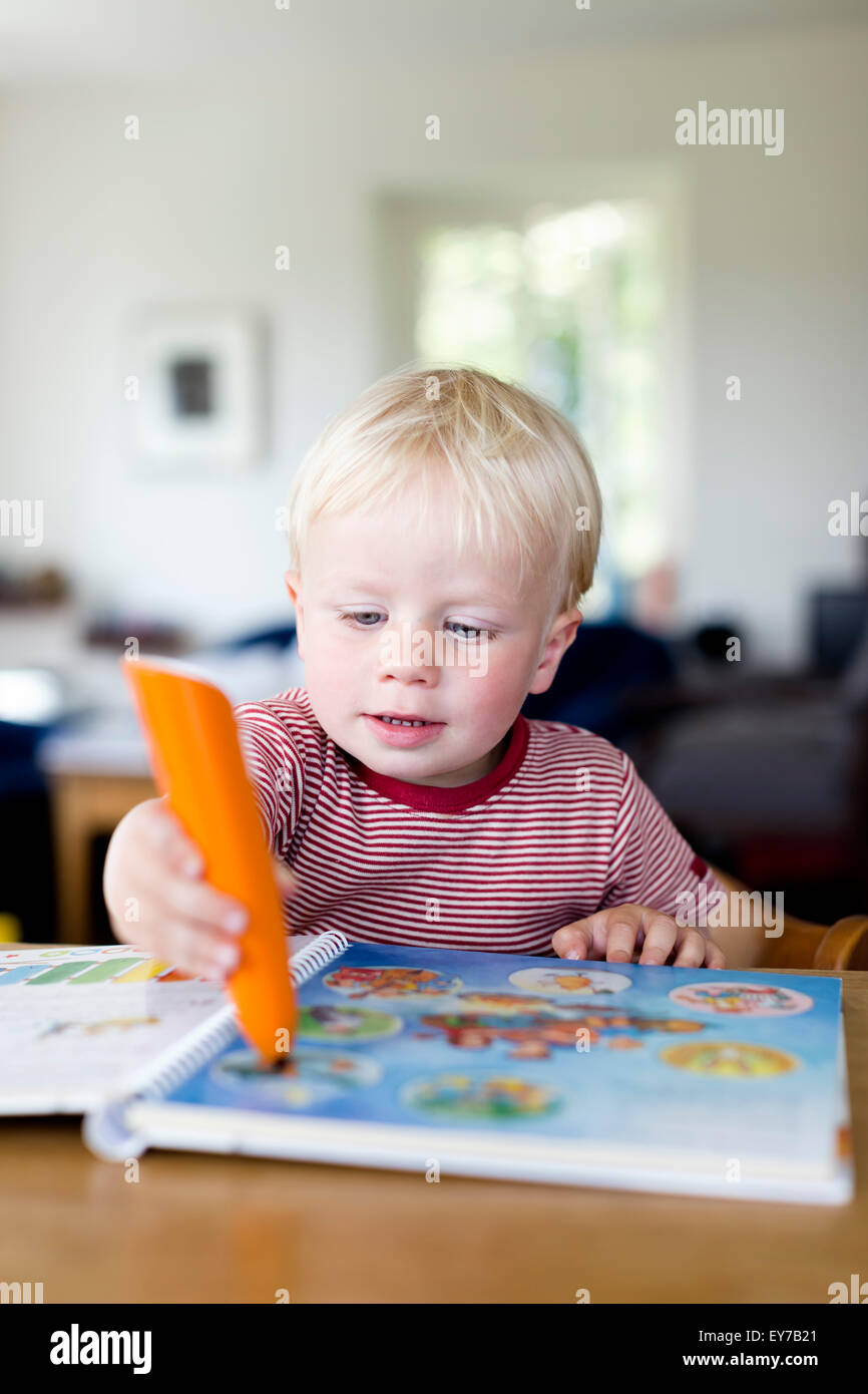 Kleiner Junge liest ein Kinderbuch mit einem elektronischen Tiptoi-Stift, was den Inhalt des Buches, das Kind erklärt. Stockfoto