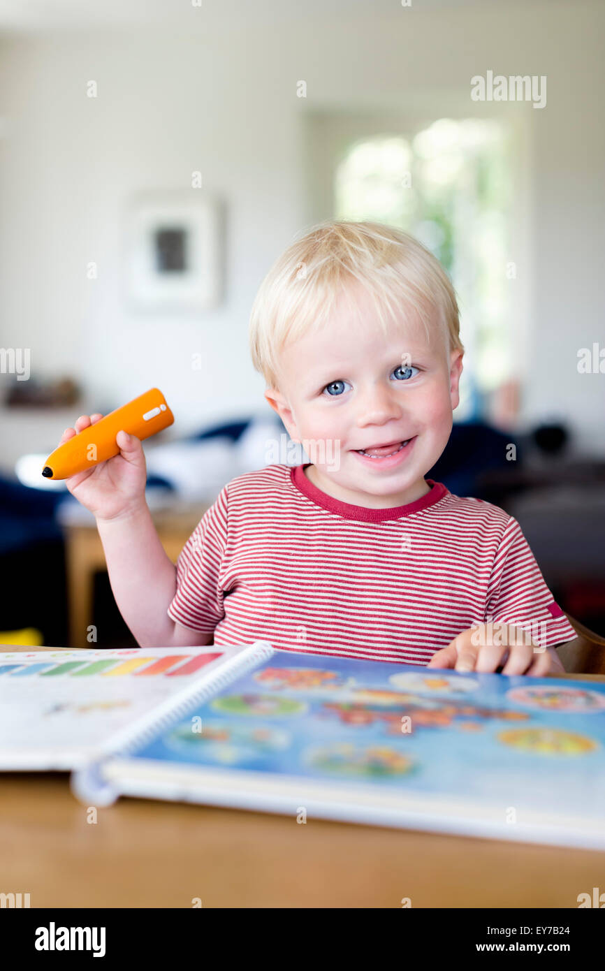 Kleiner Junge liest ein Kinderbuch mit einem elektronischen Tiptoi-Stift, was den Inhalt des Buches, das Kind erklärt. Stockfoto