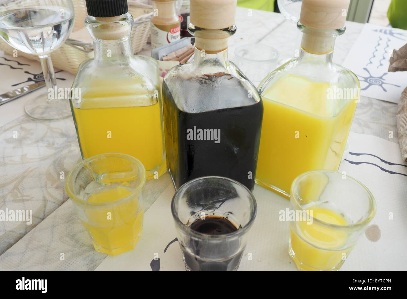 Drei Flaschen und drei Gläser Liköre auf einem Tisch. Stockfoto