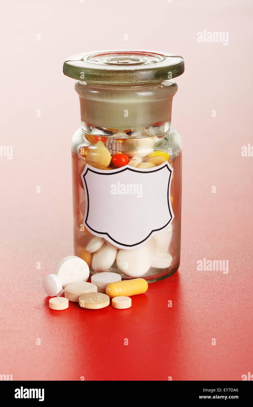 Pillen vor chemischen Glasflasche mit leere Beschriftung, gefüllt mit bunten Pillen Stockfoto