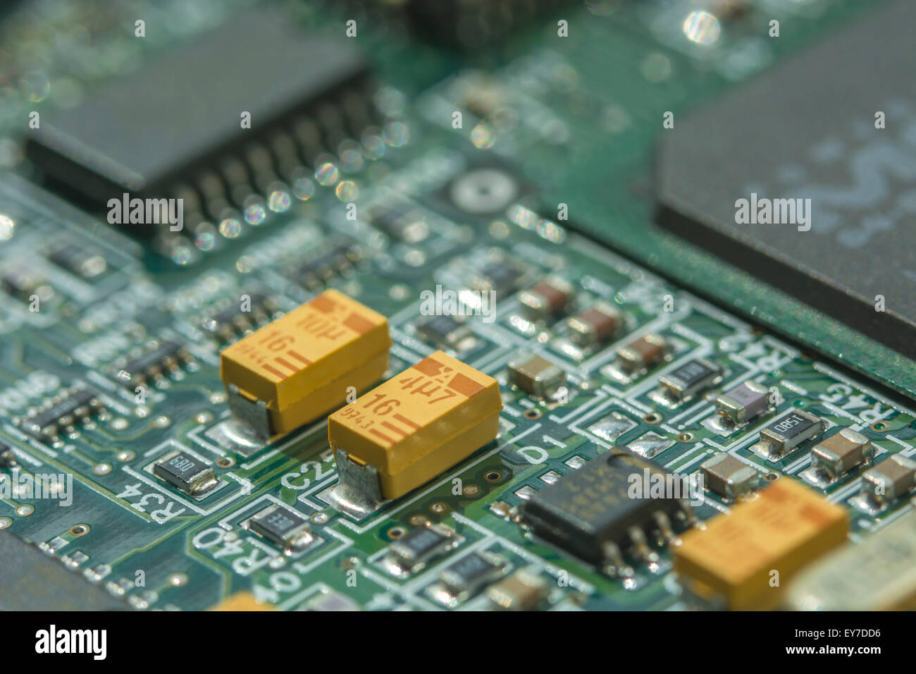 Makrofoto der Leiterplatte (PCB) mit gelben Tantal-Oxidkondensatoren (eine Seltene Erden). Nahaufnahme des Schaltkreises, Detail einer Leiterplatte. Stockfoto