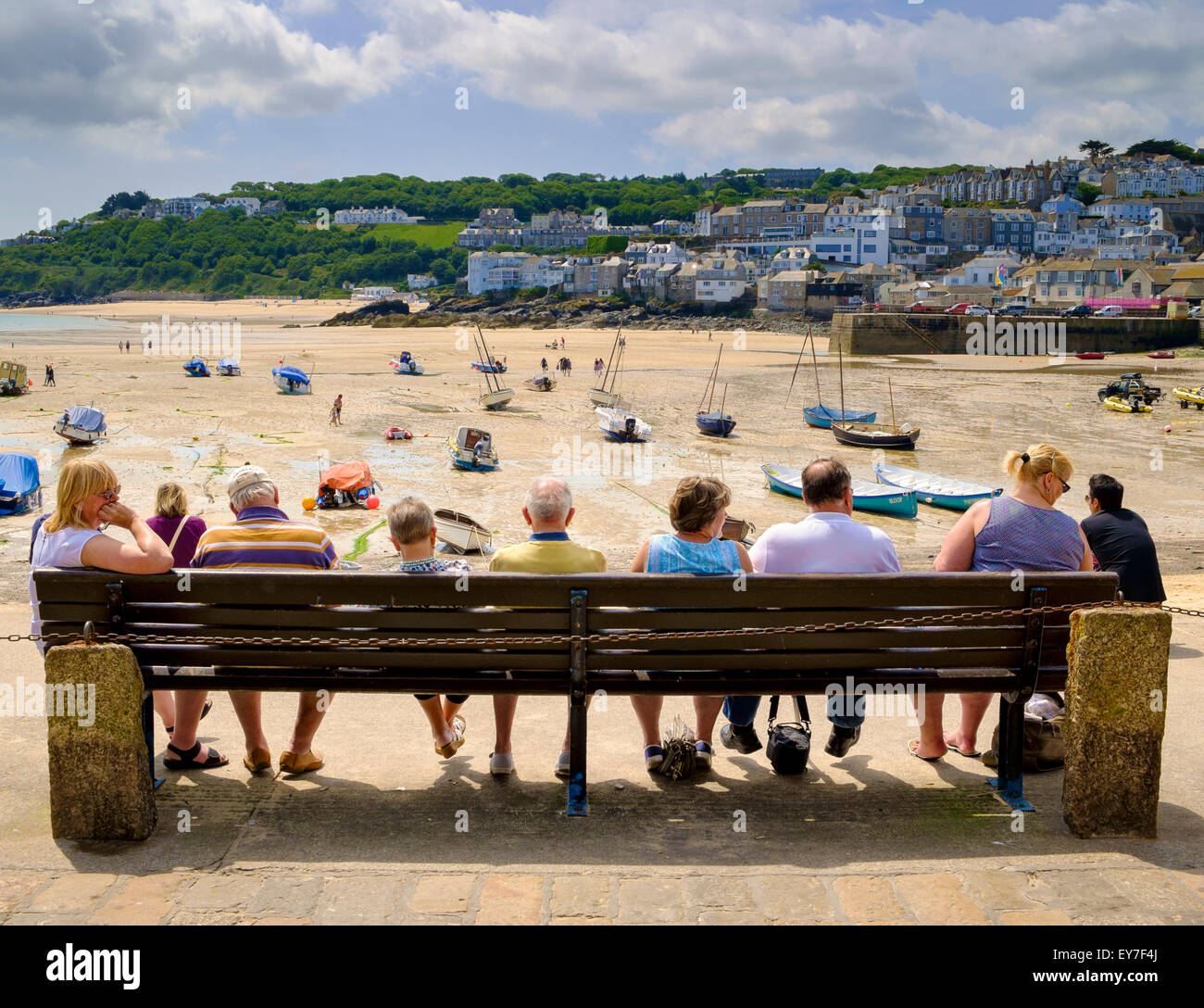 Cornwall im Sommer - Menschen Touristen sitzt auf der Bank mit Blick auf den Hafen und Strand Meer in St Ives, Cornwall, England, Großbritannien im Sommer Stockfoto
