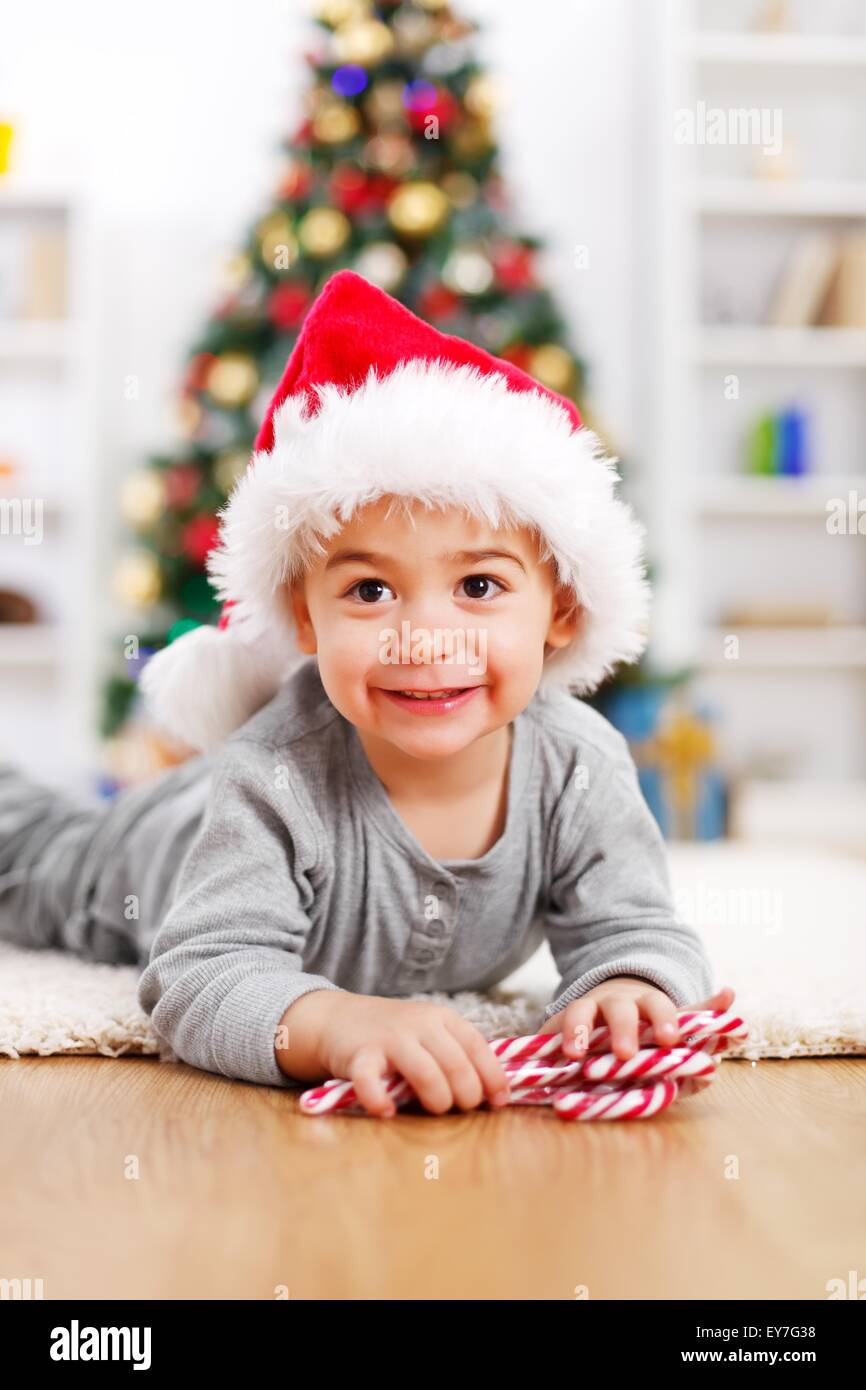 Süsser Boy Verlegung vor geschmückter Weihnachtsbaum Stockfoto