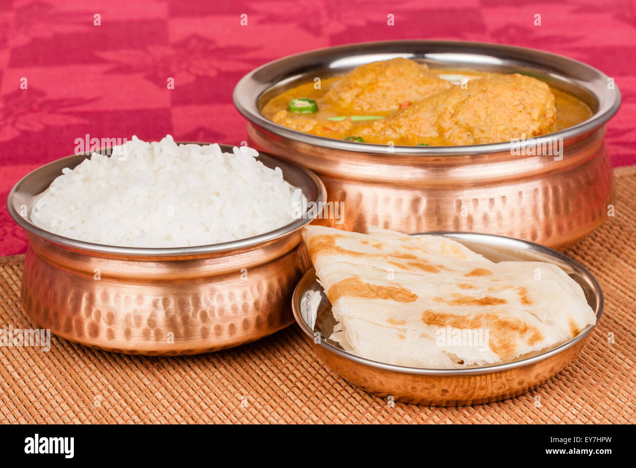 Indischer Chicken curry Mahlzeit mit Reis & Parotta (indisches Brot) in authentischen Kupfer Utensilien. Grüne Chili als Garnitur verwendet. Stockfoto