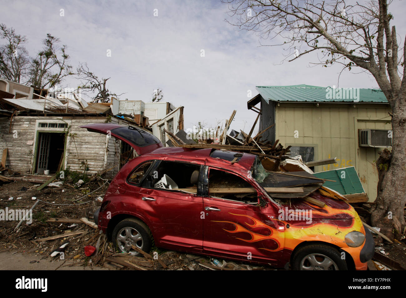 Ein stark beschädigtes Auto mit einer Flamme Lackierung vor einem Haus in Mississippi nach dem Hurrikan Katrina. Stockfoto