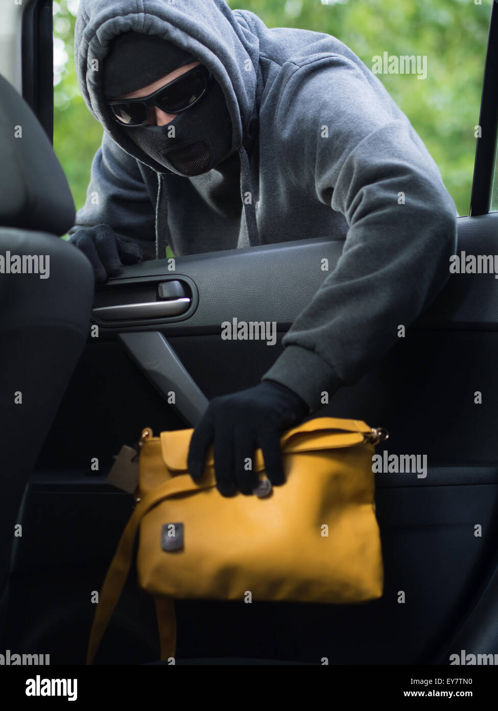 Verkehrskonzept Verbrechen. Dieb stiehlt Tasche aus dem Auto Stockfoto