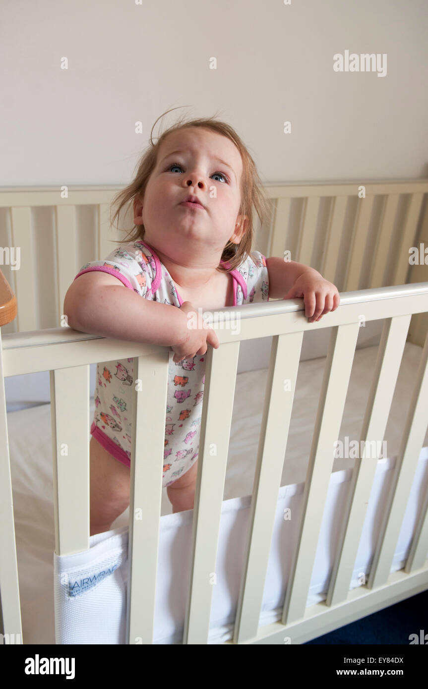 Babymädchen auf der Suche über den Lenker von ihrem Kinderbett Stockfoto