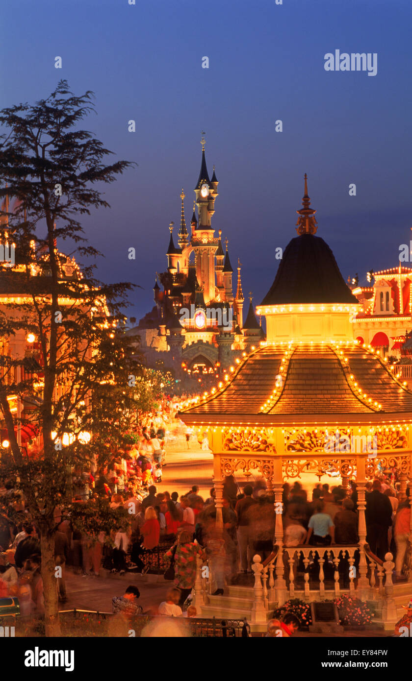 Das Schloss mit Main Street mit ihren Geschäften und Menschen in der Dämmerung Licht im Euro Disney Resort außerhalb von Paris Stockfoto