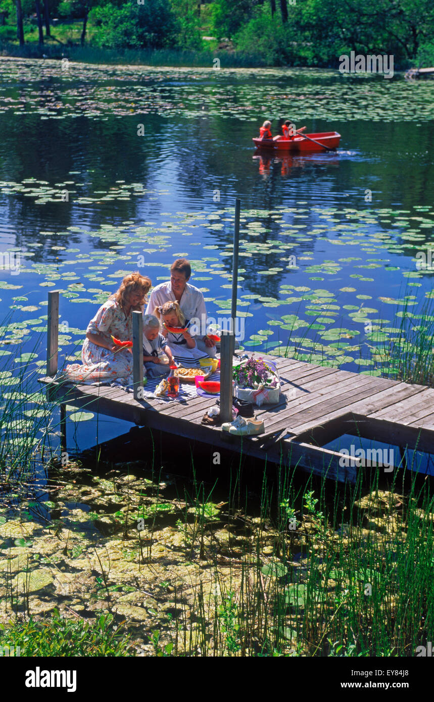 Vierköpfige Familie mit Picknick-Korb auf See Pier im schwedischen Sommer Stockfoto