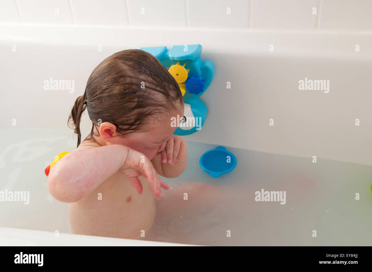 Kleinkind in der Badewanne ihre Augen reiben Stockfoto