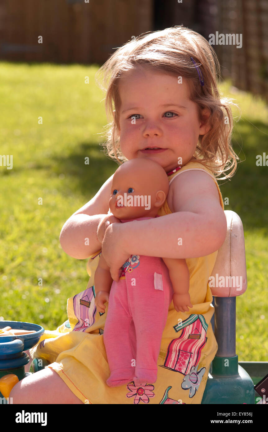 Porträt eines Mädchens umarmt ihr Puppe suchen zufrieden Stockfoto