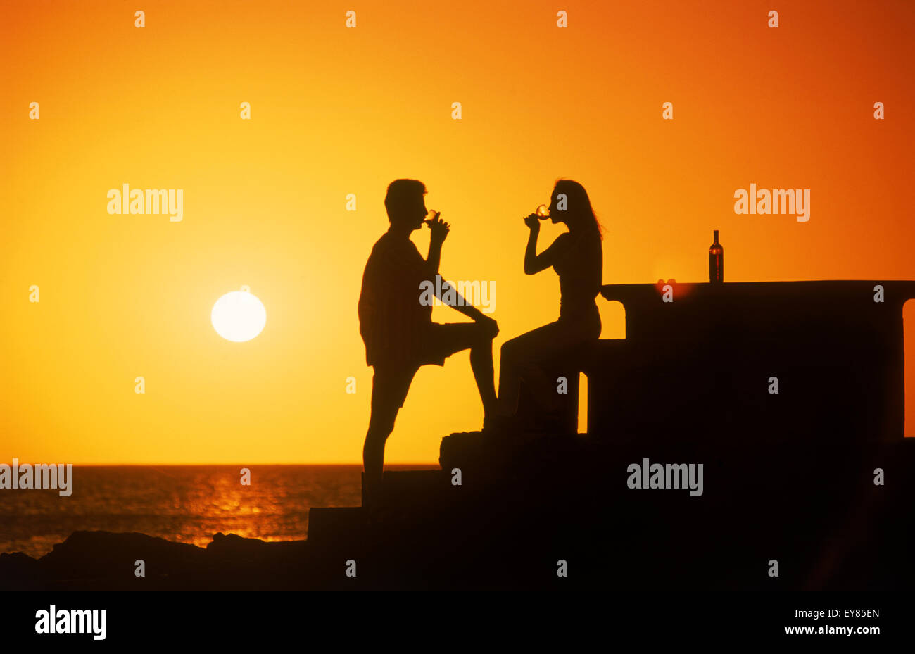 Paar genießt ein Glas Wein bei Sonnenuntergang entlang der Küste von Uruguay Stockfoto