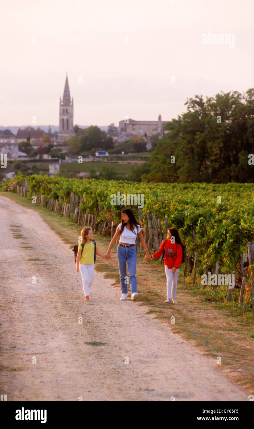 Mutter und Töchter, vorbei an Weinbergen von Bordeaux am Weg zur Schule im Dorf von St. Emilion, Frankreich Stockfoto