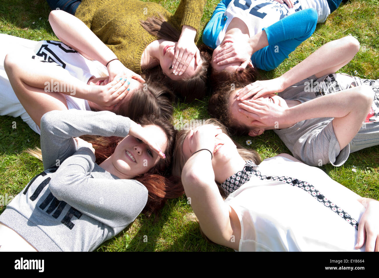 Glückliche Gruppe von Mädchen im Teenageralter liegen in einem Kreis mit ihren Händen über ihre Augen Stockfoto