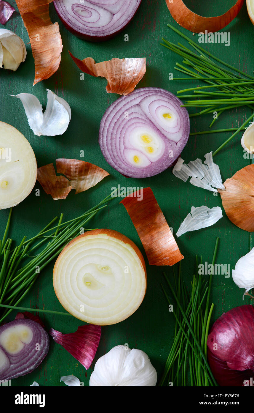 Zwiebeln, Schnittlauch und Knoblauch verstreut auf alten grünen Holztisch für die Zubereitung von Speisen und Koch-Konzept. Stockfoto