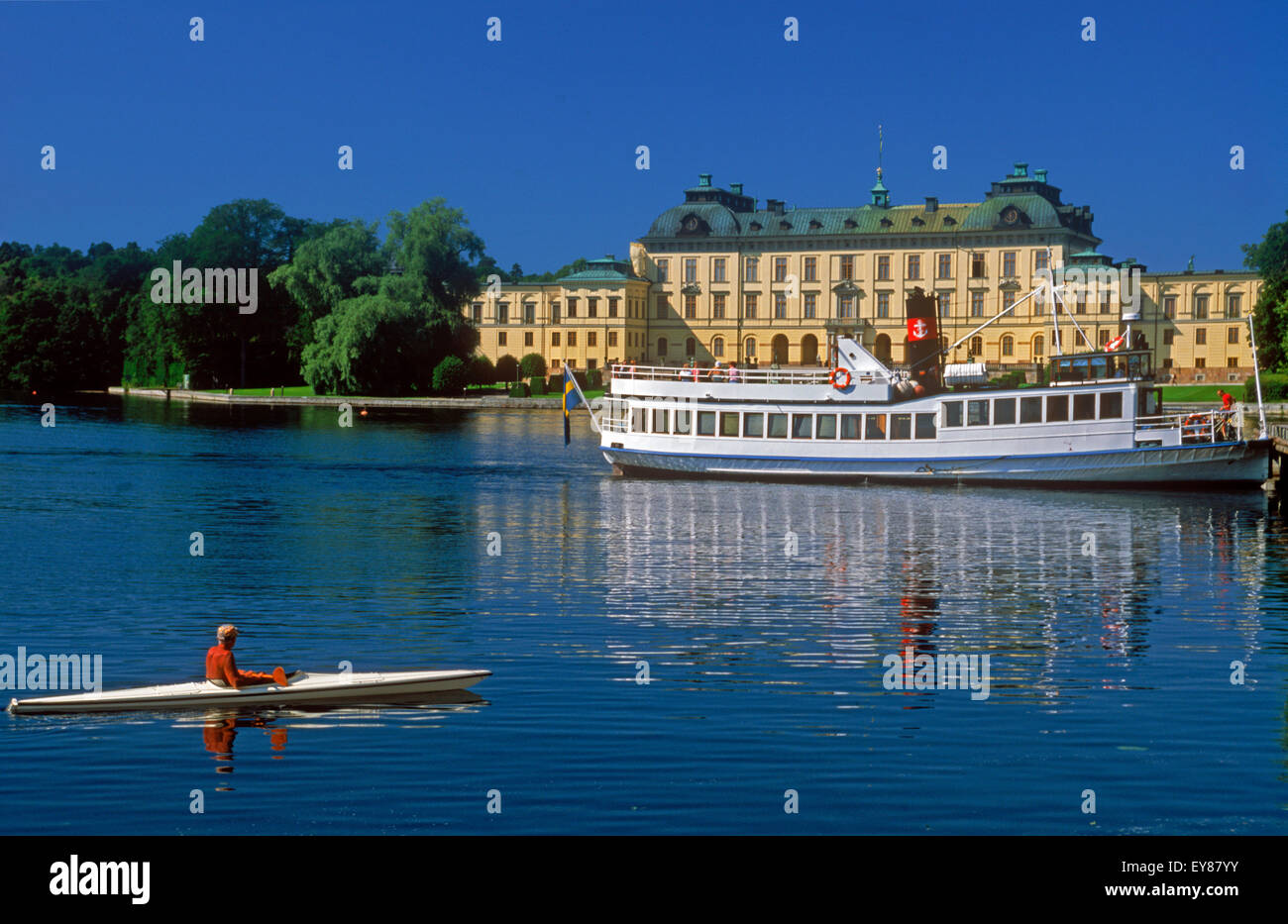 Fähre und Kajak auf ruhigem Wasser vor der königlichen Residenz in Drottningholm Palace in der Nähe von Stockholm an Sommertag Stockfoto