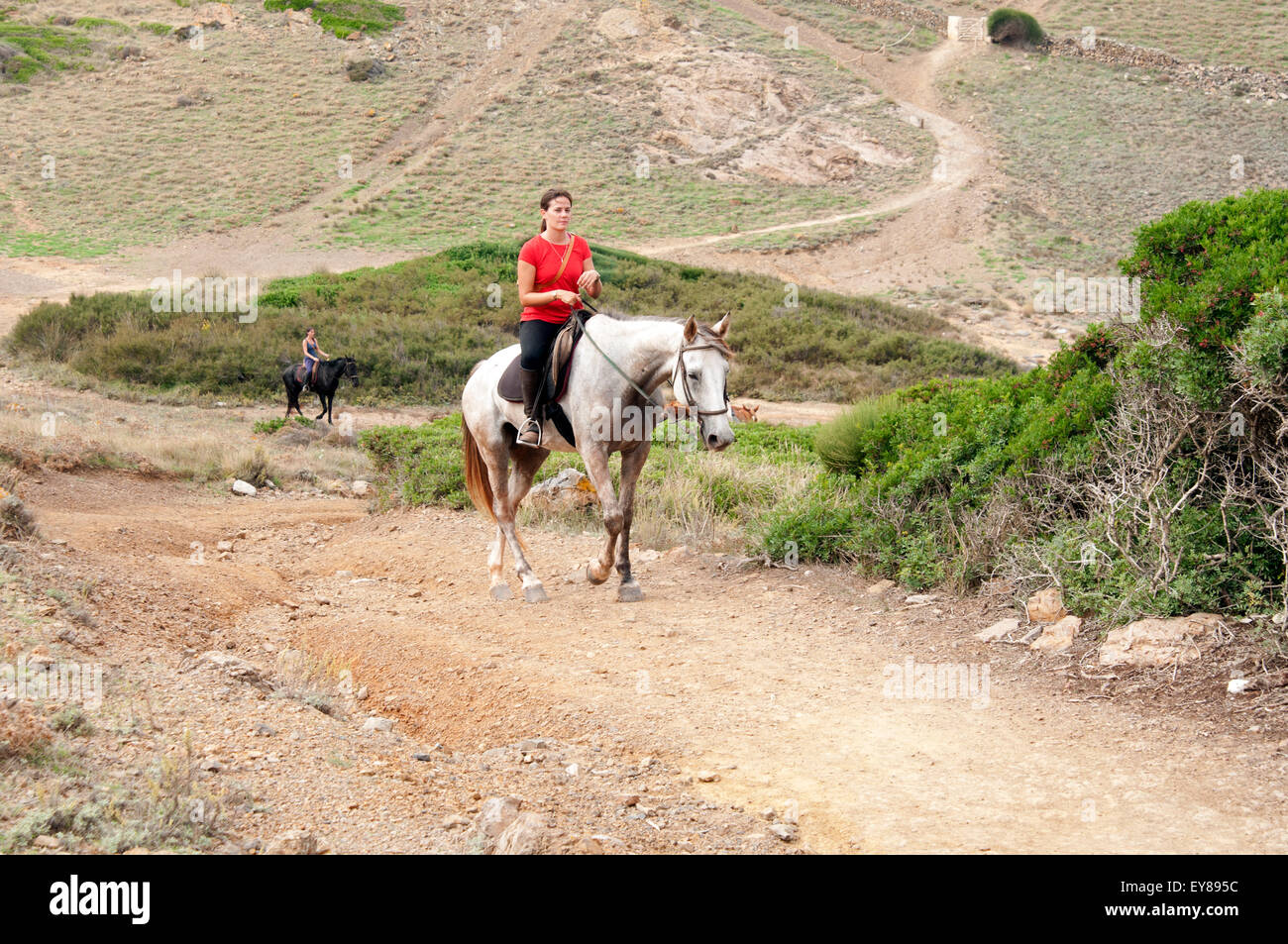 Eine Gruppe von Reitern, die von einem jungen hübschen geführt werden Das spanische Mädchen reitet auf ihrem Pferd entlang der Cami de Cavalls Auf der Insel Menorca Spanien Stockfoto