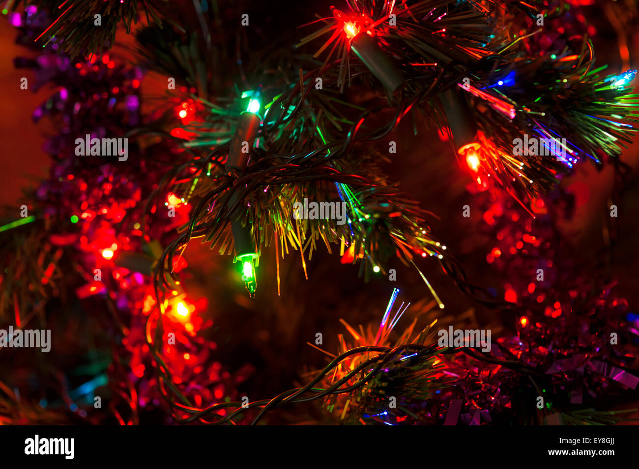 Bunter Weihnachtsbaum Nahaufnahme mit bunten Lichtern und Dekoration ein warmes festliche rote Glühen umgeben. Stockfoto