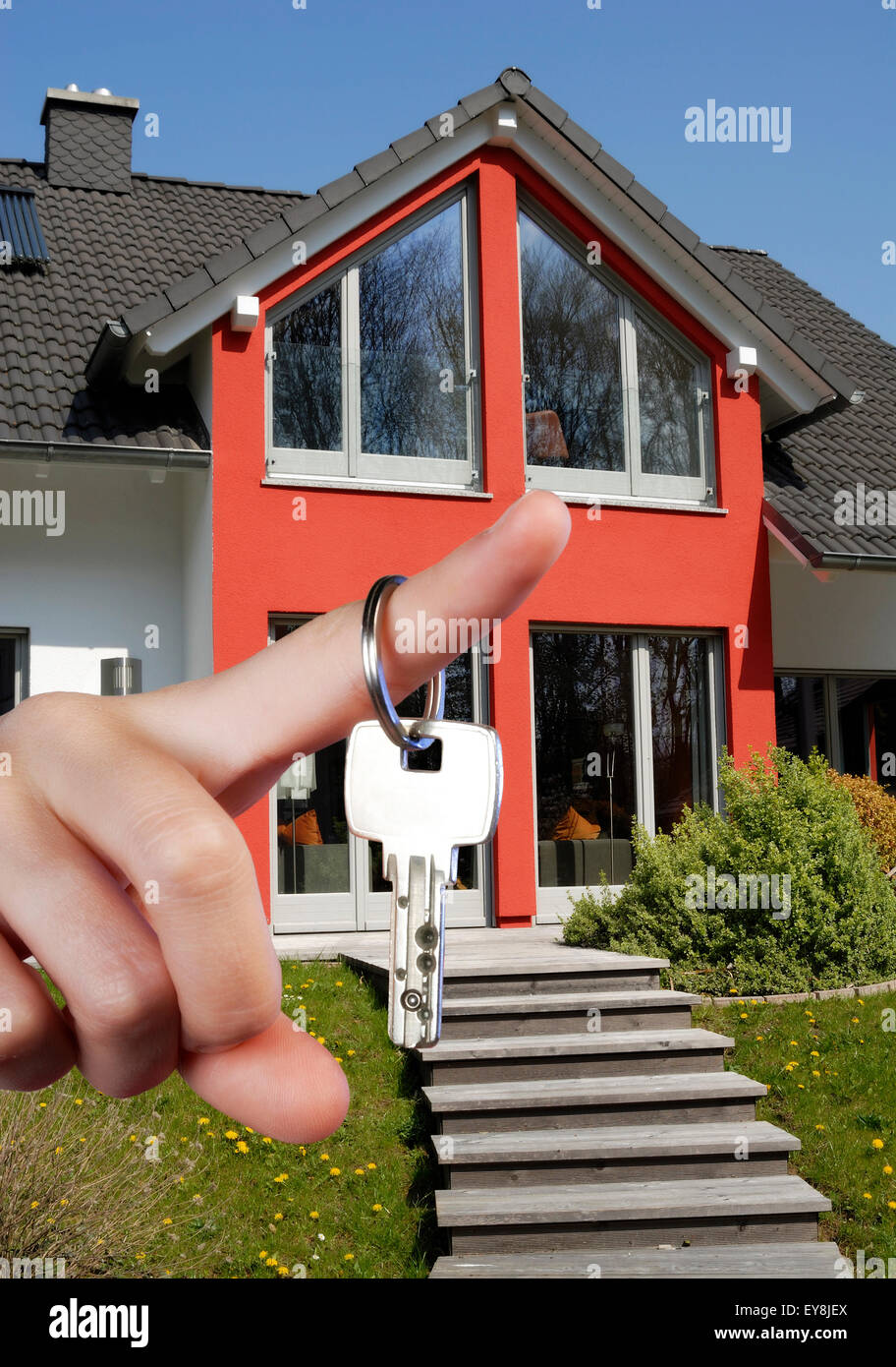 Schlüssel wird auf einem Finger vor einem Haus gehalten. Stockfoto