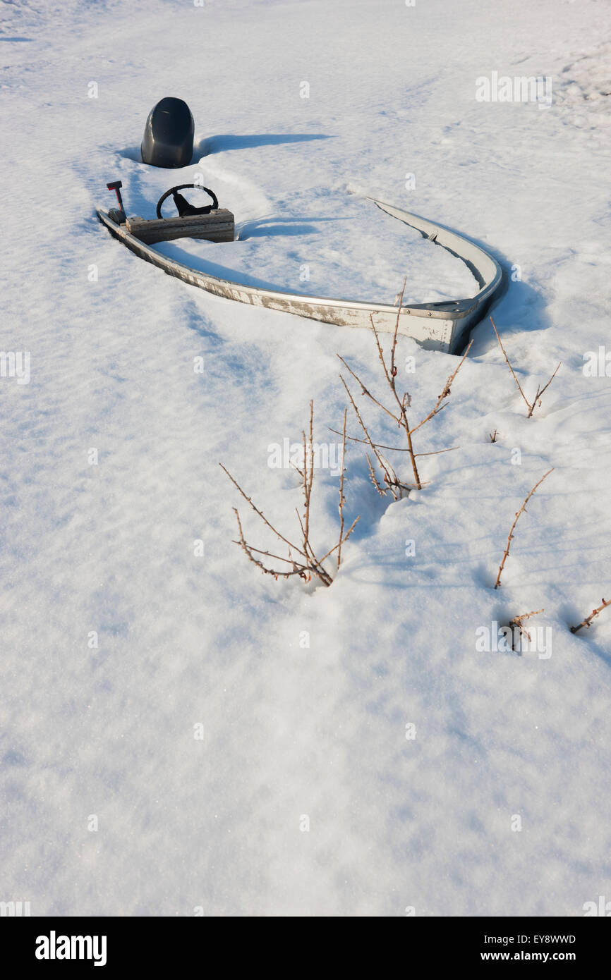 Boot mit einem Außenbordmotor im Schnee begraben; Noatak, Alaska, Vereinigte Staaten von Amerika Stockfoto