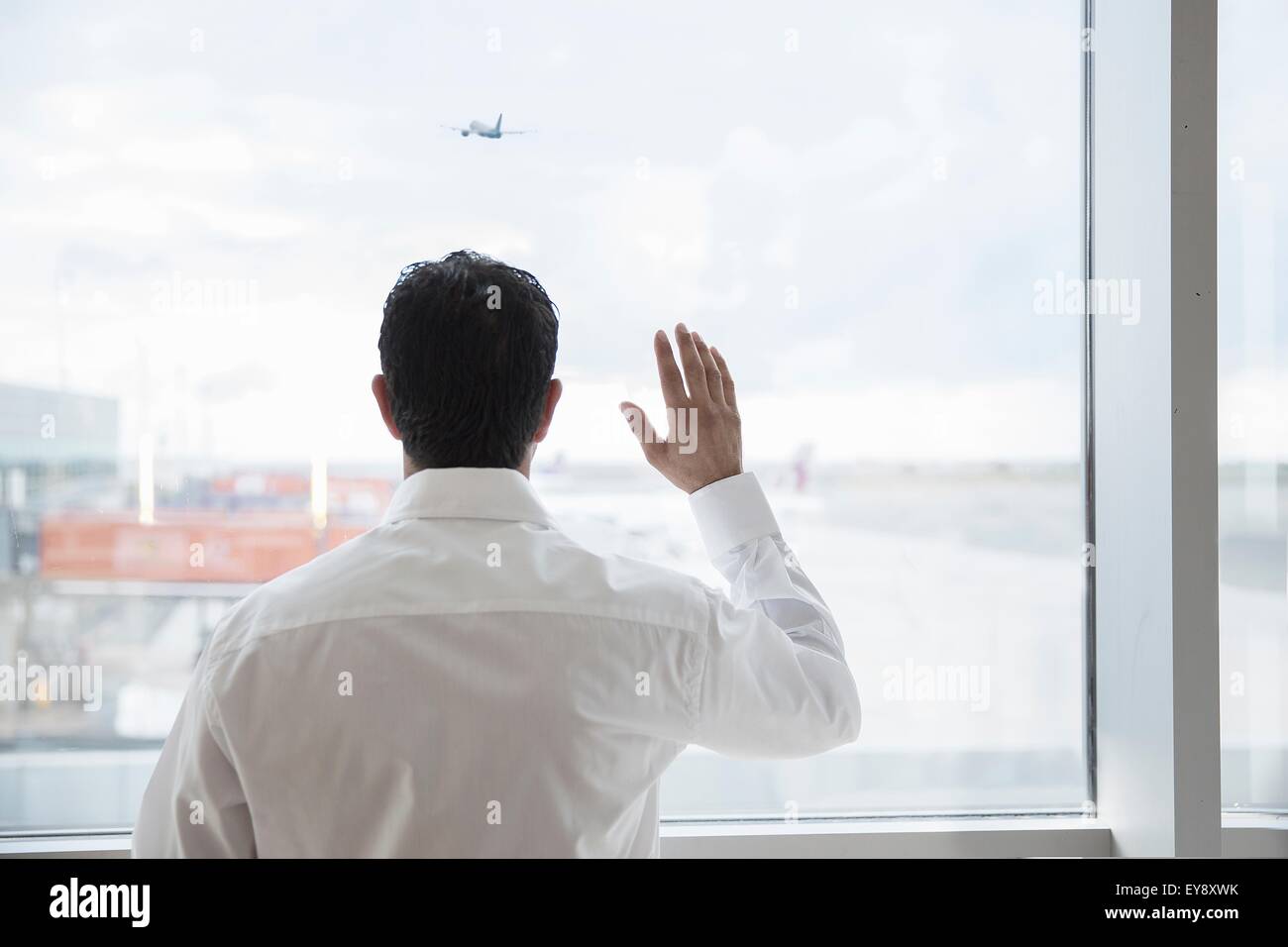 Mann am Flughafen Fenster winken Stockfoto