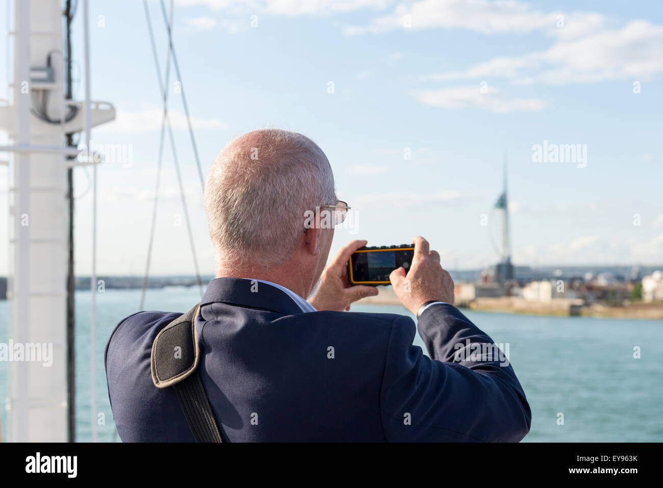 mittleren gealterten männlichen stehen auf dem Deck der Fähre Rückblick auf Portsmouth und sein Iphone Smartphone verwenden, um ein Foto zu machen Stockfoto
