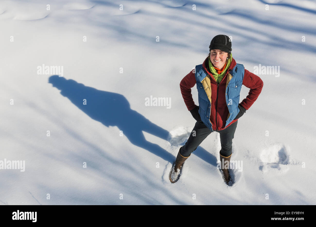 Eine lächelnde junge Frau trägt eine Mütze und Handschuhe steht in einem Snowbank, Winter, Yunan Alaska, USA Stockfoto