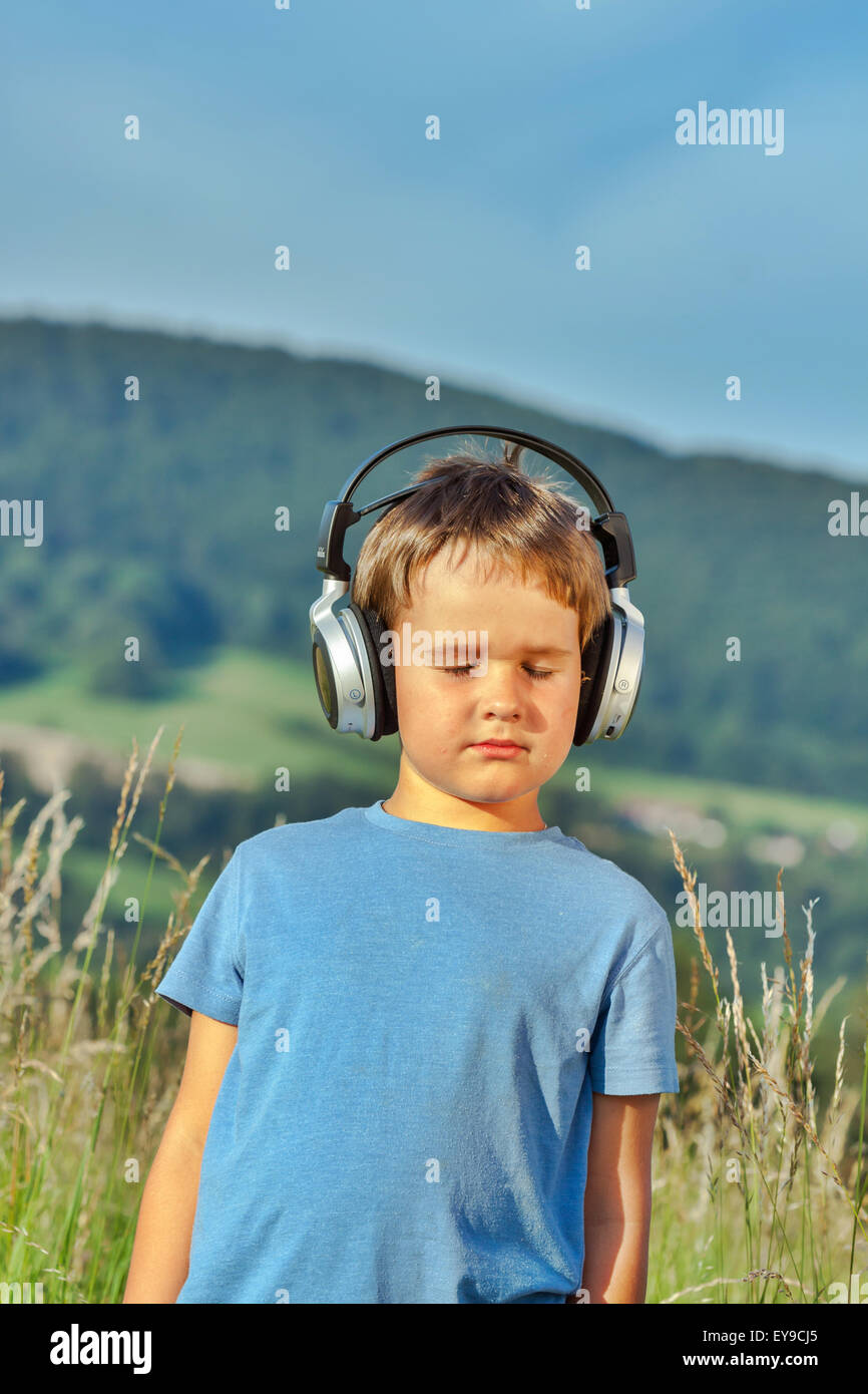 Süßen 6-jährigen Jungen anhören von Musik über Kopfhörer in der Natur Stockfoto