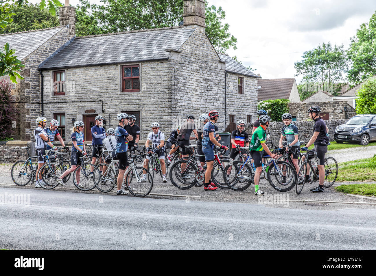 Gruppe von Radfahrern mit Fahrrädern treffen auf der Straße vor einem Stein Schule im Peak District, an einem Rennen teilnehmen Stockfoto