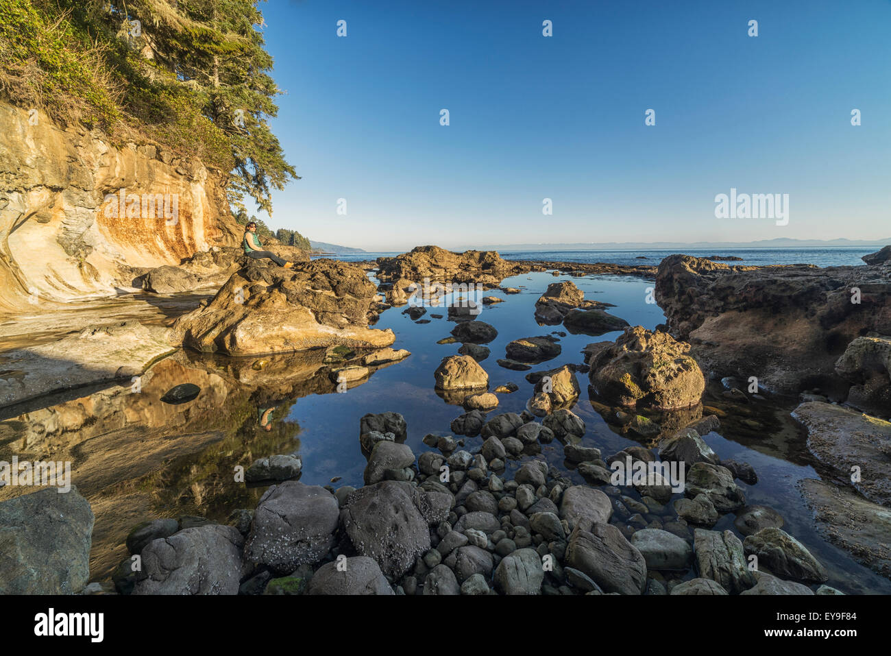 Frau sitzt auf den Felsen am Botanical Beach in der Nähe von Port Renfrew; Vancouver Island, British Columbia, Kanada Stockfoto