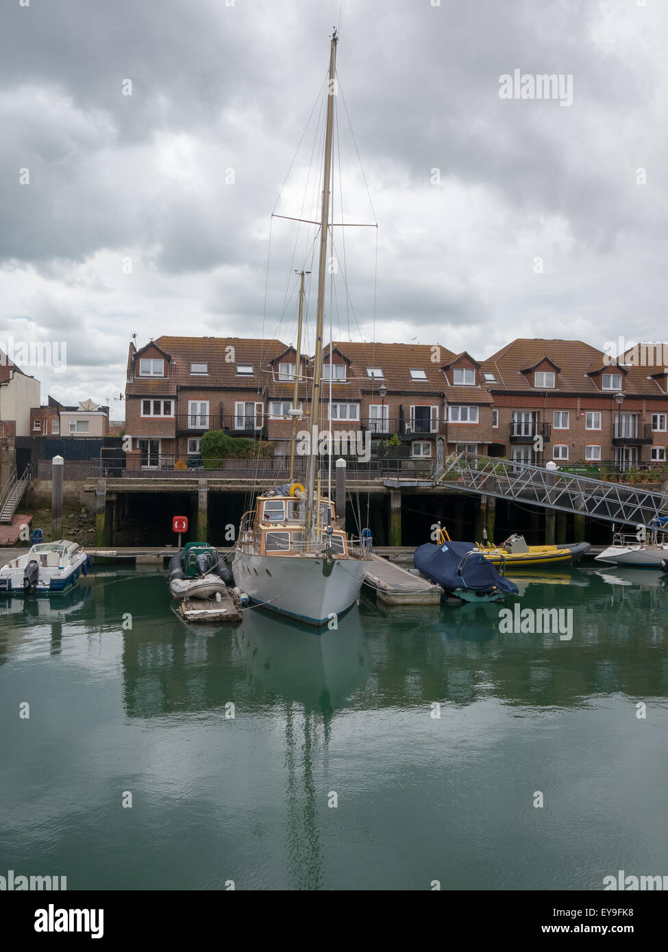 Ein Freizeit-Segelboot vor Anker in eine private Anlegestelle neben Gehäuse in Camber Docks, Old Portsmouth, England Stockfoto