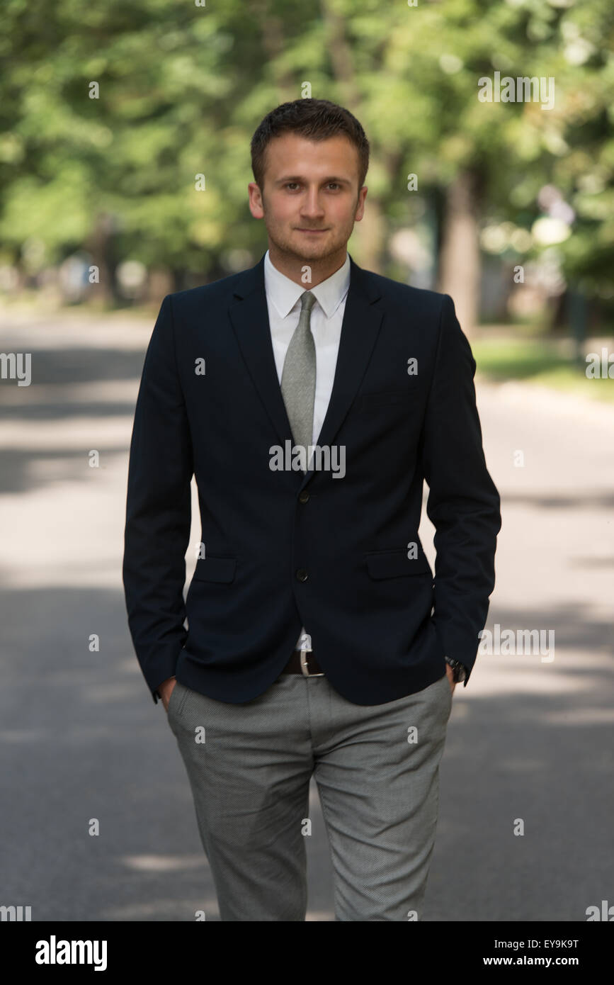 Junger Geschäftsmann zu Fuß draußen im Park beim Ausruhen von der Büroarbeit Stockfoto