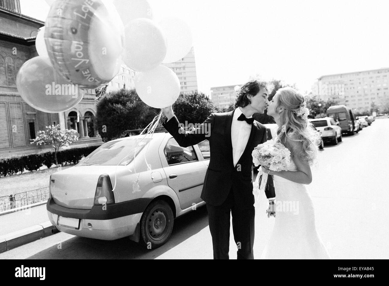 Just married junge Paar küssen auf einer Straße. Schwarz / weiß Bild mit Korn Film als Effekt hinzugefügt. Stockfoto