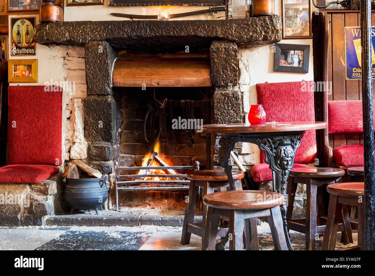 Brennholz Kamin mit Feuer, alte Holzstühle und Metall Beinen Holztisch; Athlone, Grafschaft Westmeath, Irland Stockfoto