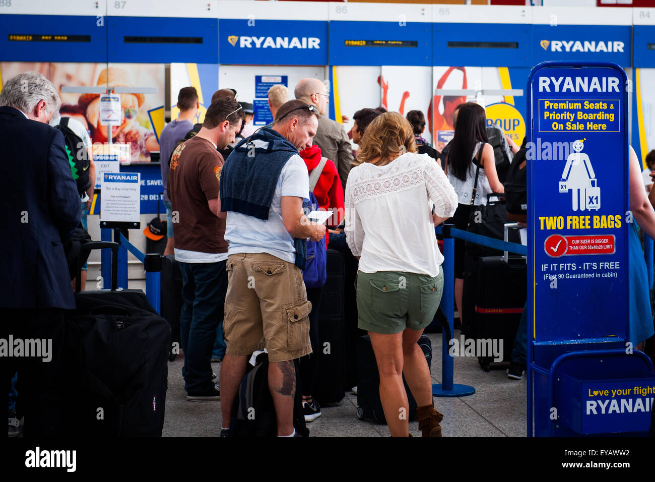 Warteschlange Passagiere Gepäck am belebten Ryan Air Check in-Schalter im Flughafen Stansted, UK fallen Stockfoto