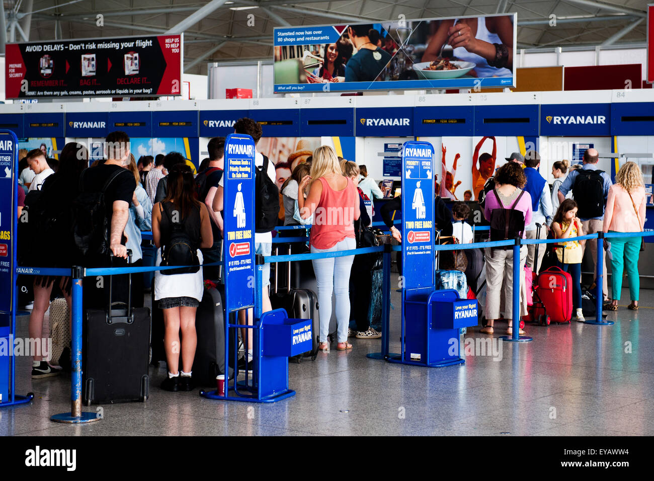 Warteschlange Passagiere Gepäck am belebten Ryan Air Check in-Schalter im Flughafen Stansted, UK fallen Stockfoto
