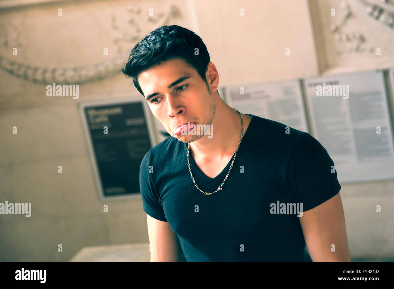 Hübscher Jüngling in Plain Black Shirt Looking Down in traurigen Gesichtsausdruck mit schmollend Lippen hautnah Stockfoto