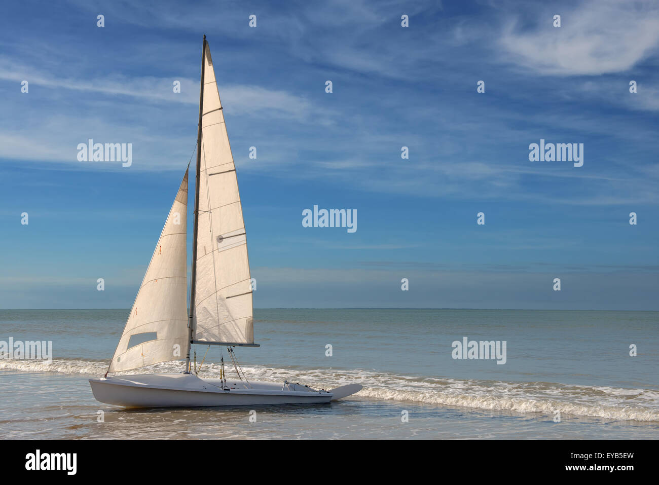 kleine weiße Segelboot geerdet an einem Strand auf blauem Hintergrund bewölkt Stockfoto