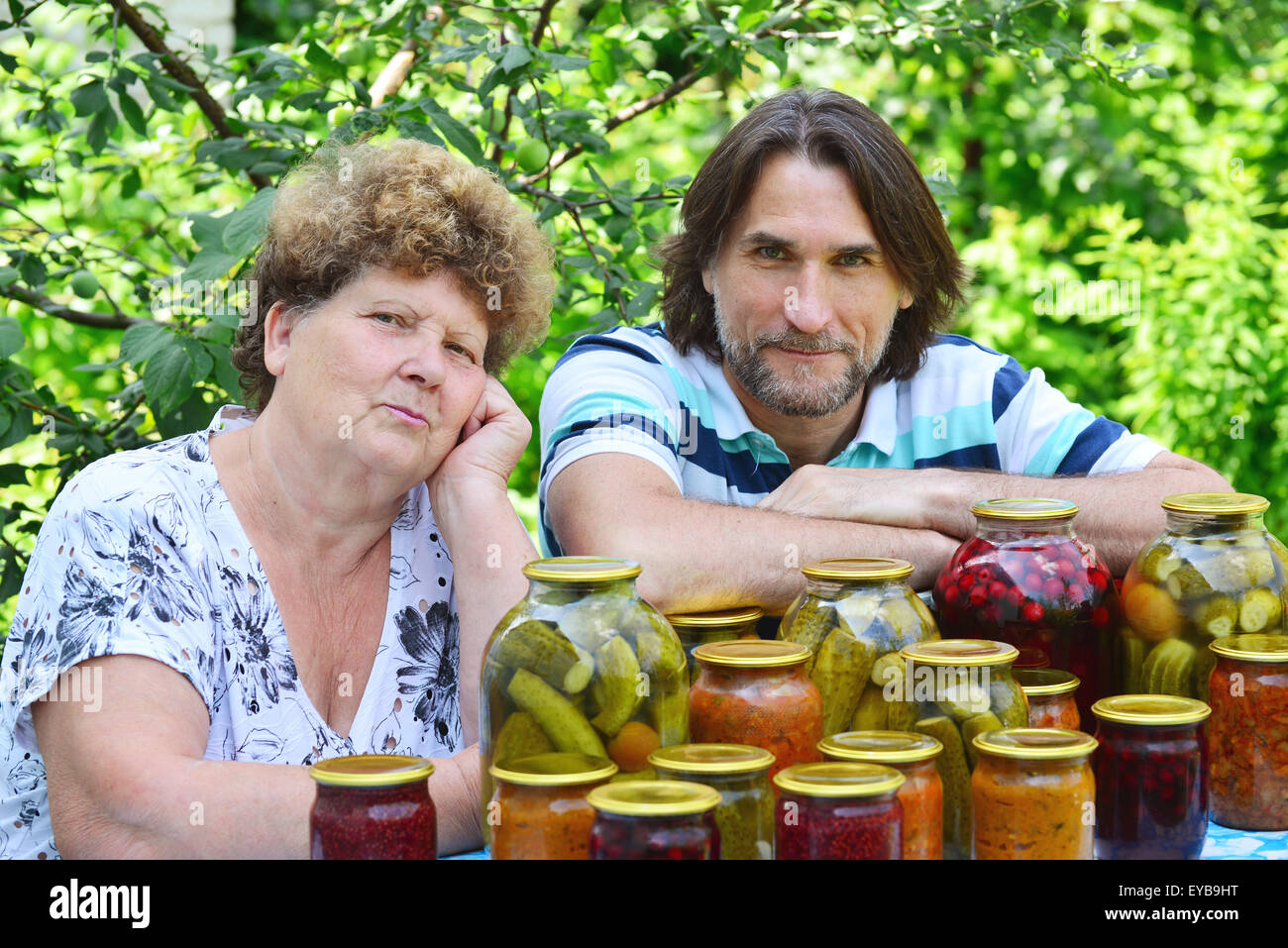 Eine ältere Frau mit ihrem Sohn am Tisch mit Gemüsekonserven Stockfoto