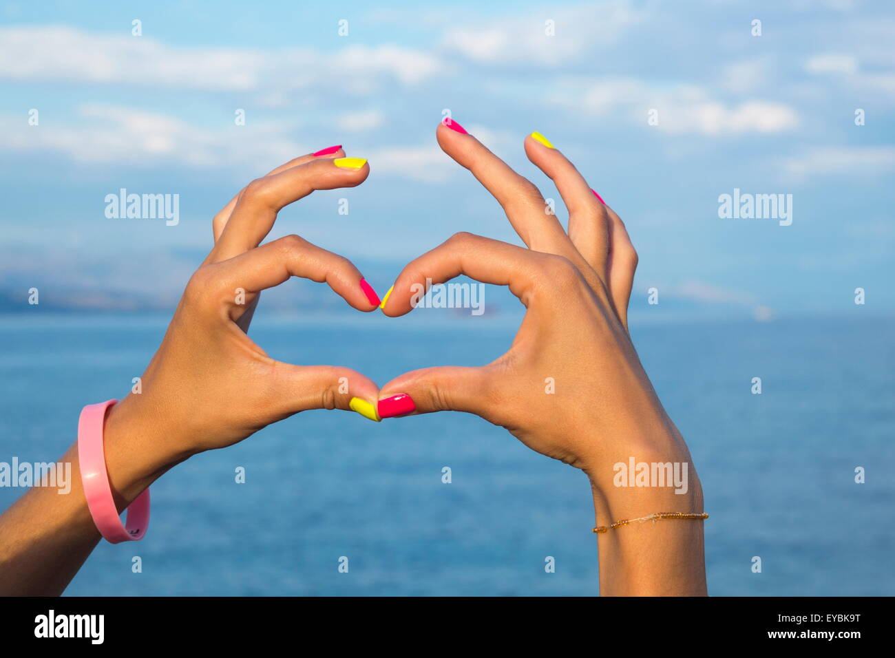 Herzform machen Hände gegen Himmel Blick auf Wasser und Meer Stockfoto