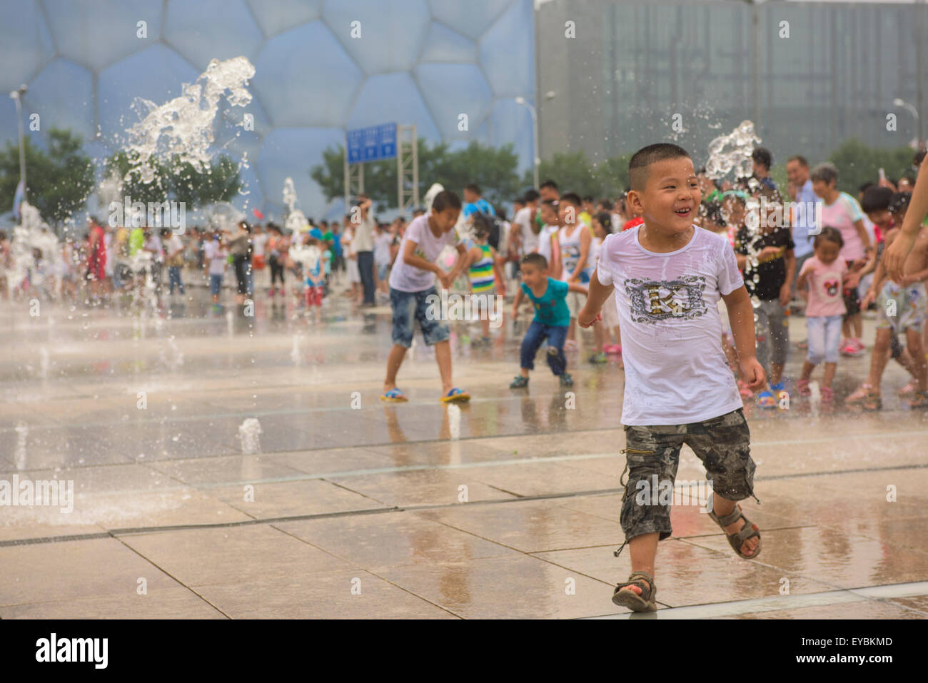 Chinesische Kinder Spaß spielen unter der Wassersprenger im Beijing Olympic Park - Juli 2015 Stockfoto