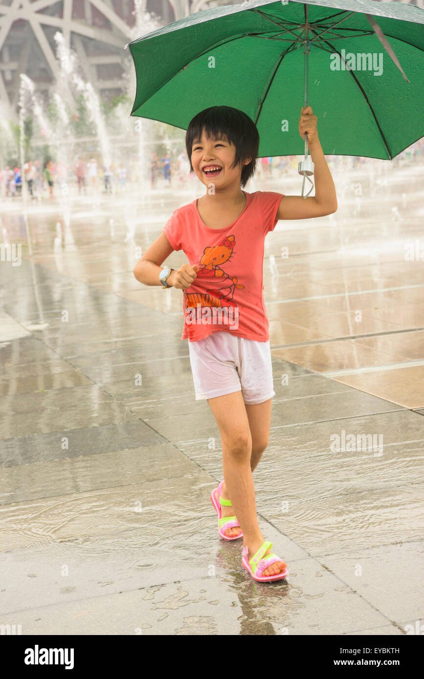 Chinesisches Mädchen spielen unter Wasser-Sprinkler vor Vogels Nest Stadium, Beijing, Juli 2015 Stockfoto