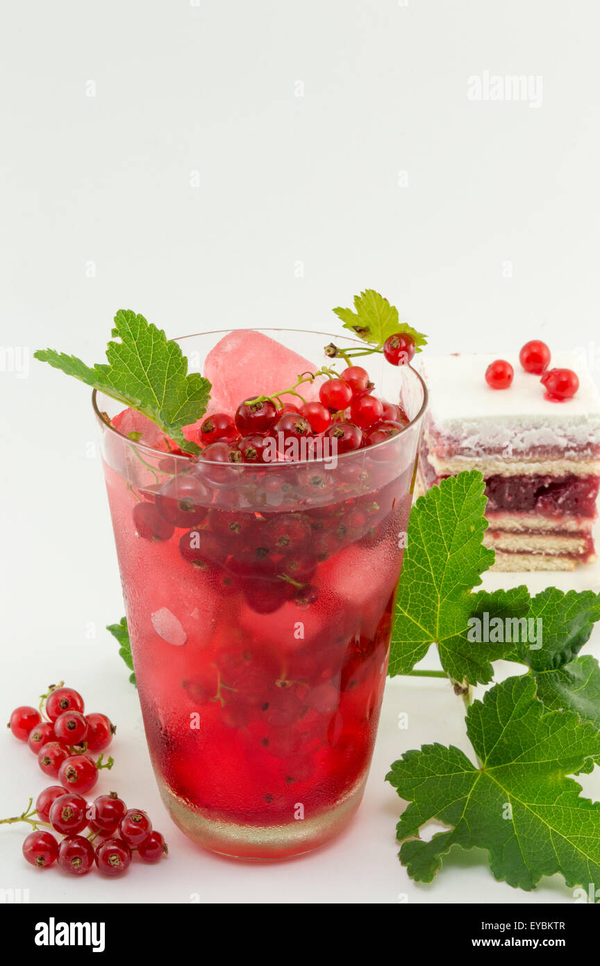 Frische Johannisbeeren iced Tea in einem Glas dekoriert mit Johannisbeere Blätter serviert mit Johannisbeeren Obstkuchen auf weiß Stockfoto